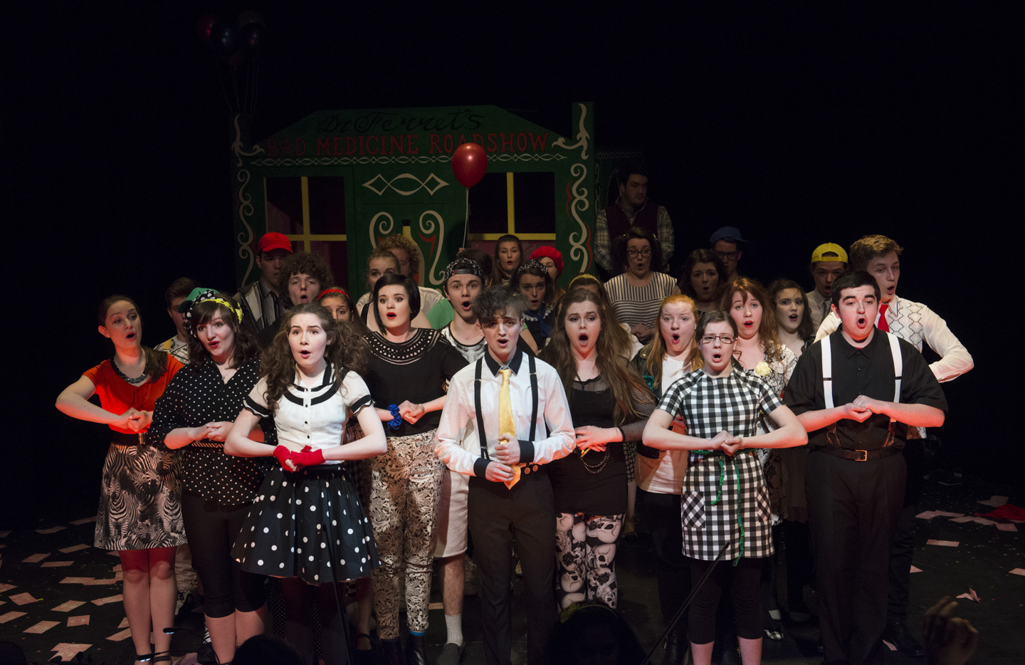 Scottish Opera's Connect Chorus standing with their hands clasped in a performance of Dr Ferret's Bad Medicine Roadshow
