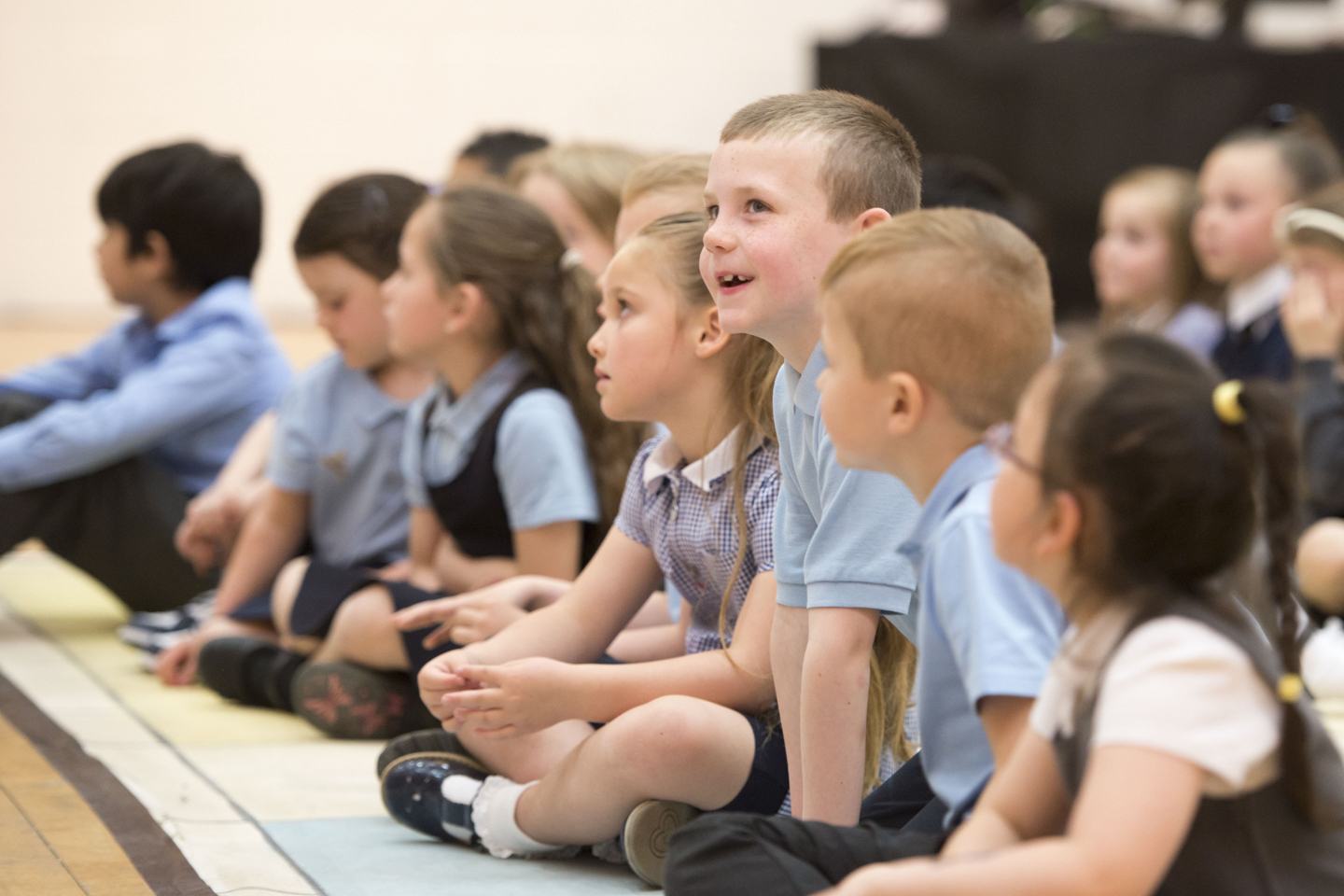 School children seated on the floor, enjoying a performance of The Little White Town of Never Weary