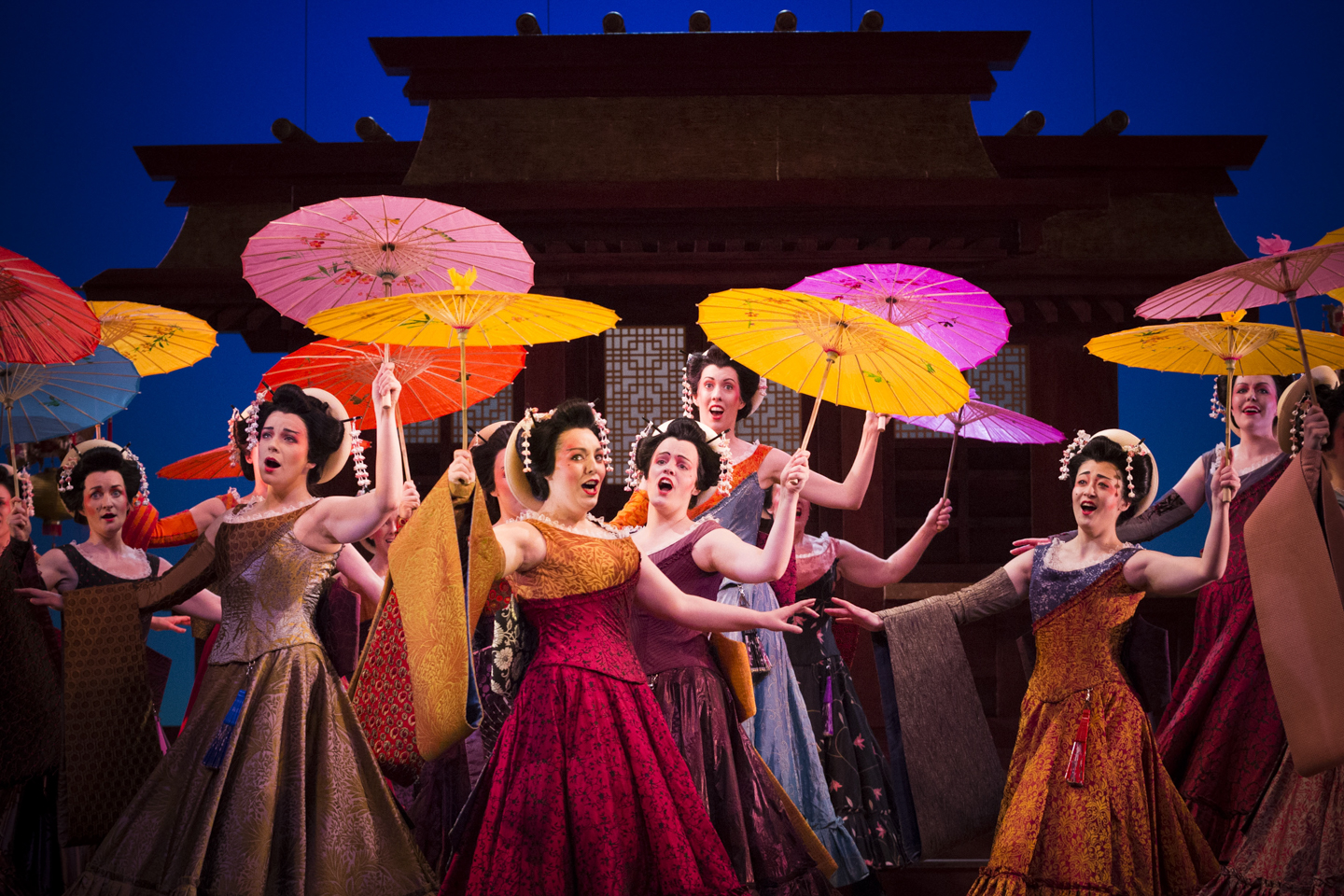 Females from the chorus of The Mikado brandishing colourful parasols