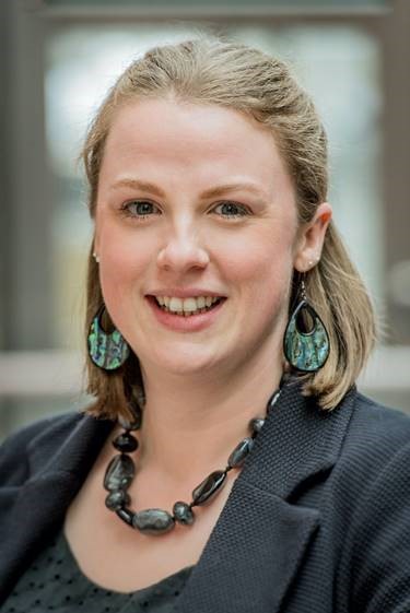 A picture of Nicola Candlish, a lady with light brown hair. She is wearing large hooped earrings and a necklace made of black stones.